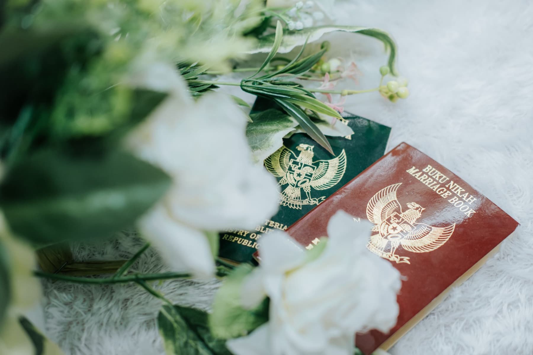 Buku nikah dan berkas tertata di samping rangkaian bunga