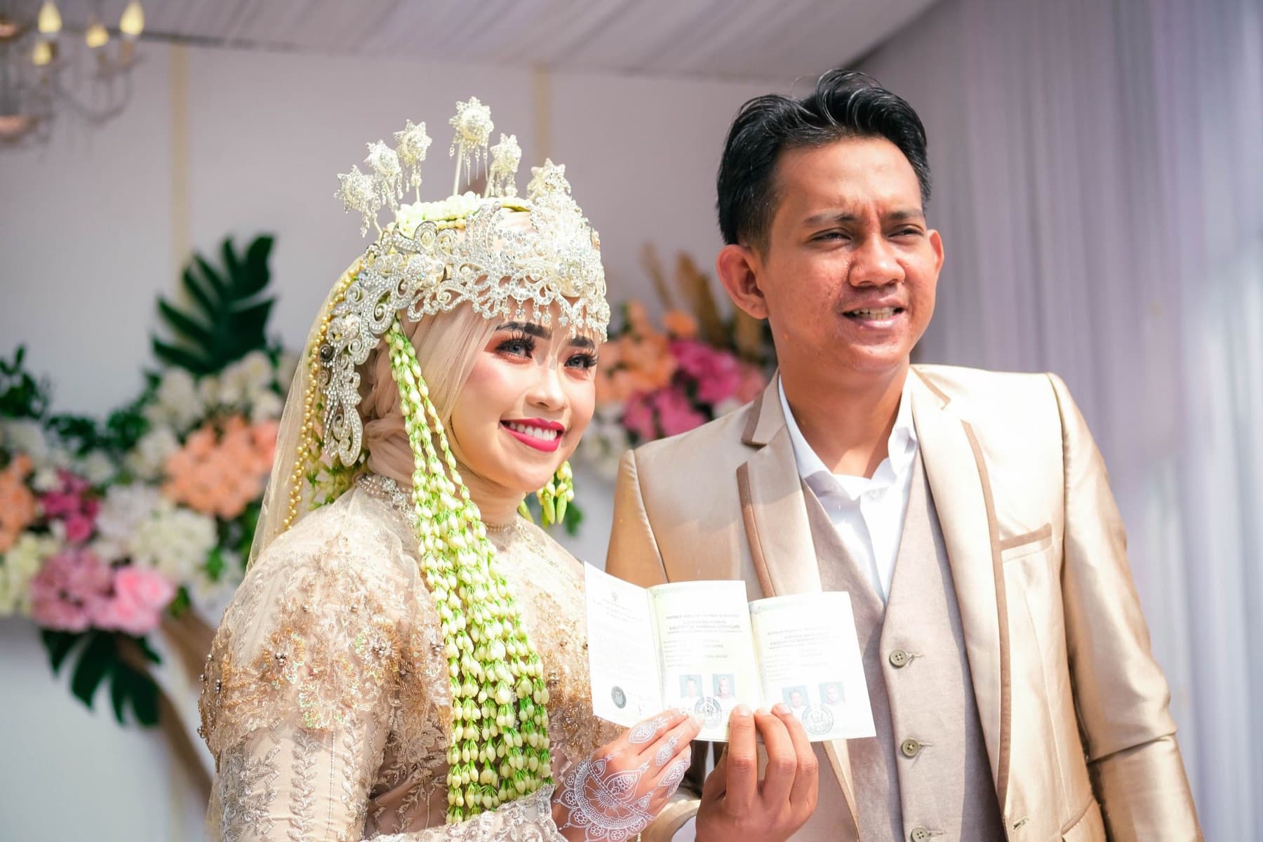 Pasangan pengantin menunjukkan buku nikah yang baru diterima